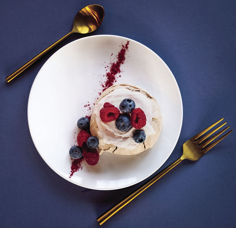 Chocolate pavlova with berries and raspberry dust